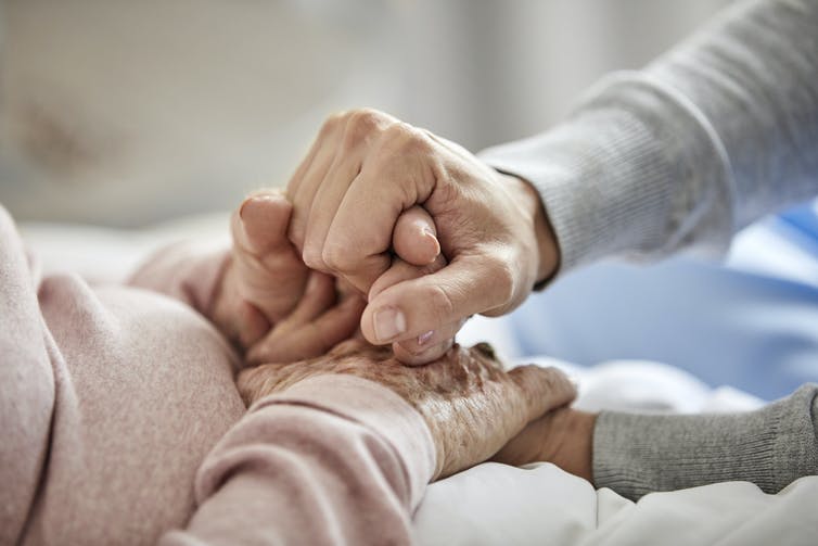 Caregiver holding the hands of an older adult.