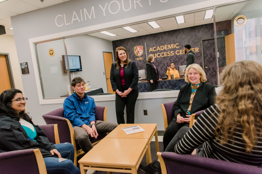 Eight people gather in an office with sign reading UMBC Academic Success Center.