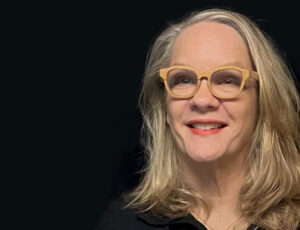 A white woman with light brown glasses.