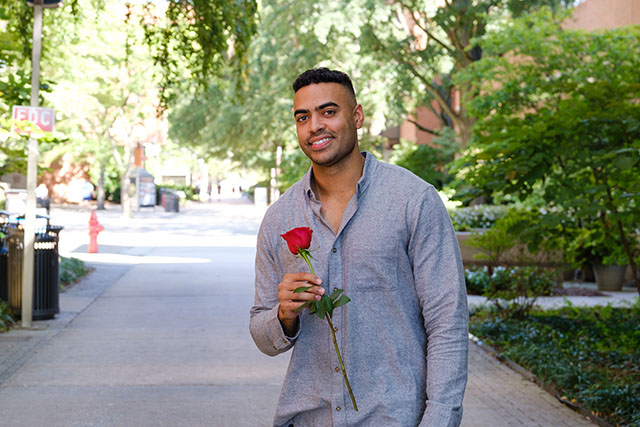 Justin Glaze poses on academic row with rose