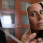 woman tests herself for corona virus in a small mirror|UMBC COVID-19 test pop up|