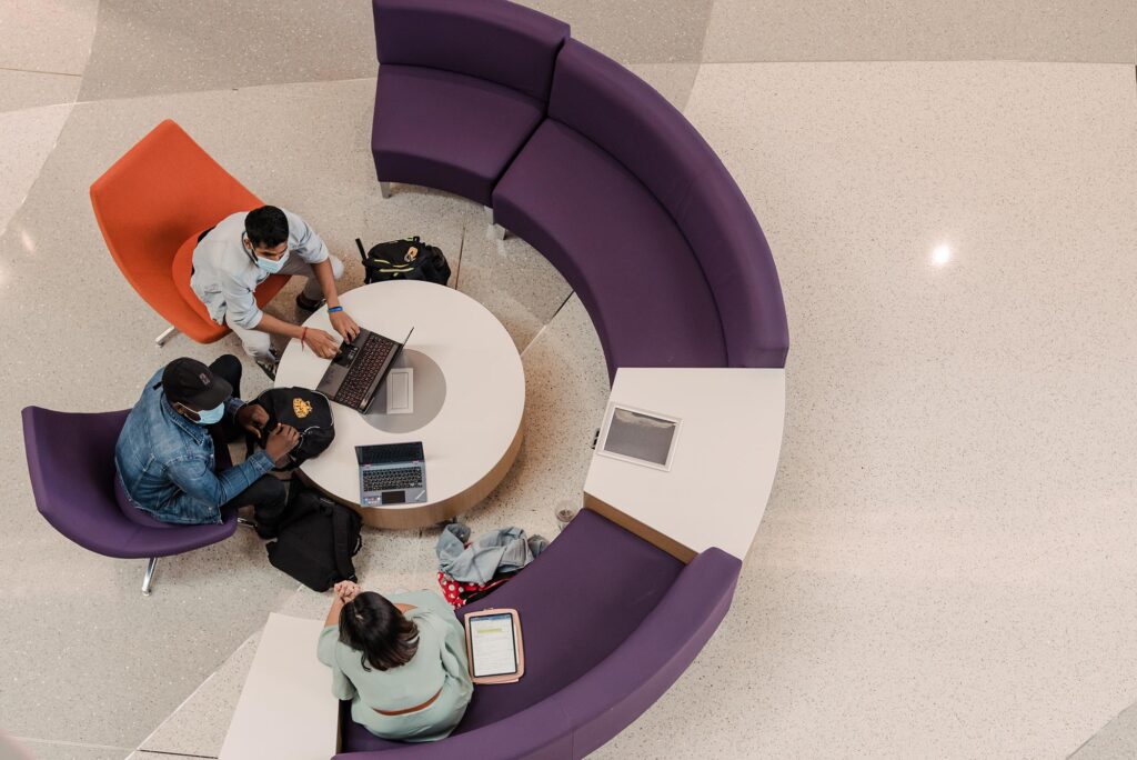 Bird's eye view of three students sitting in a circle around a table, studying together.