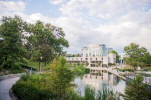 UMBC's campus in the fall, featuring the AOK Library and its reflection in a pond.