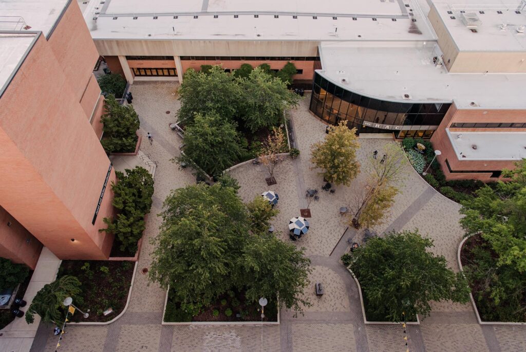 Aerial view of small area of campus with outdoor seating and trees.