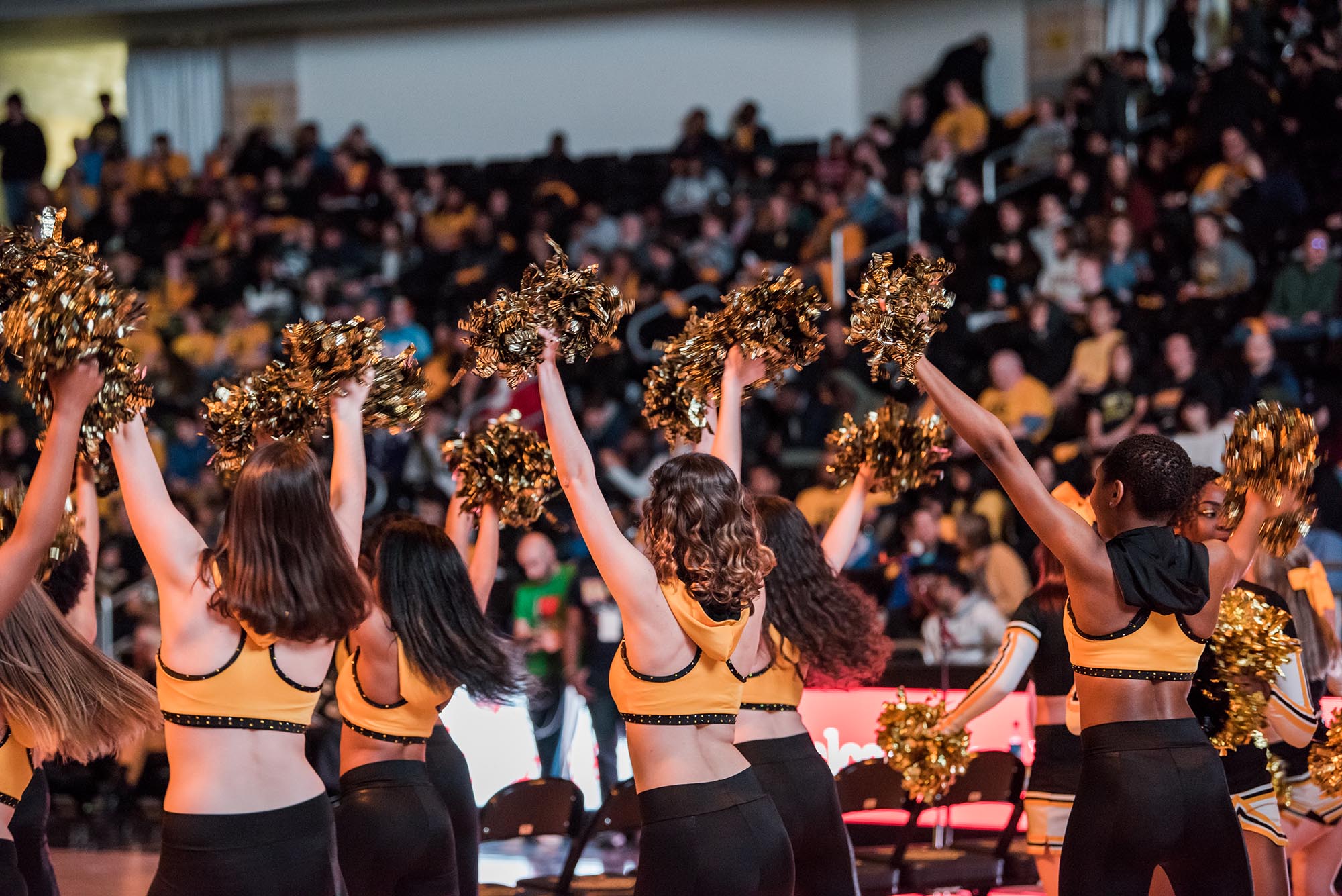 UMBC is known for having lively basketball games. Pictured here is a group of cheerleaders dancing in front of a large audience.