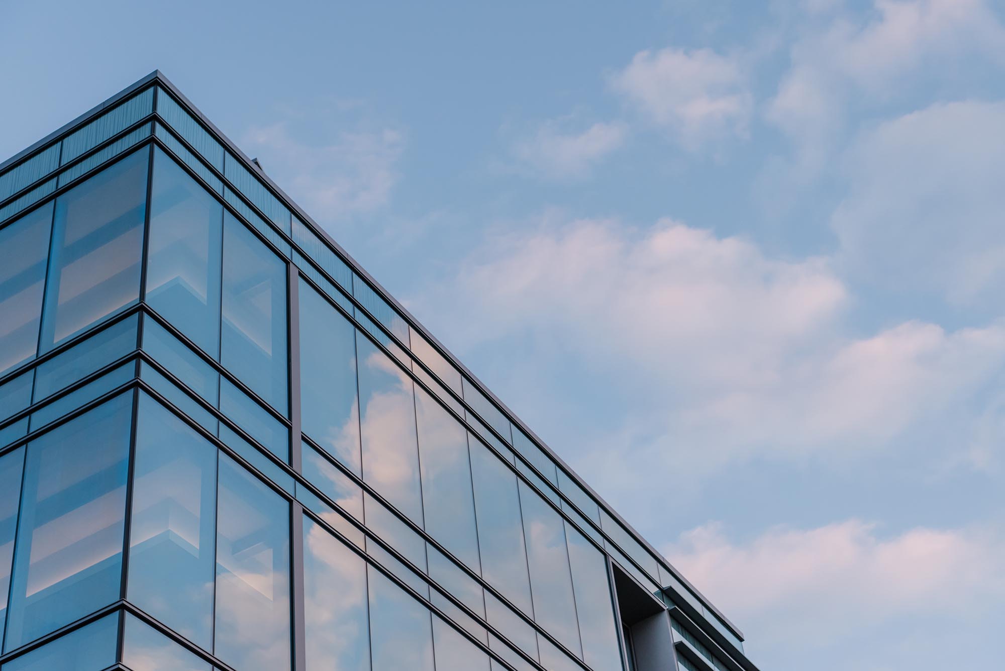 View of glass building with blue sky reflecting off it.