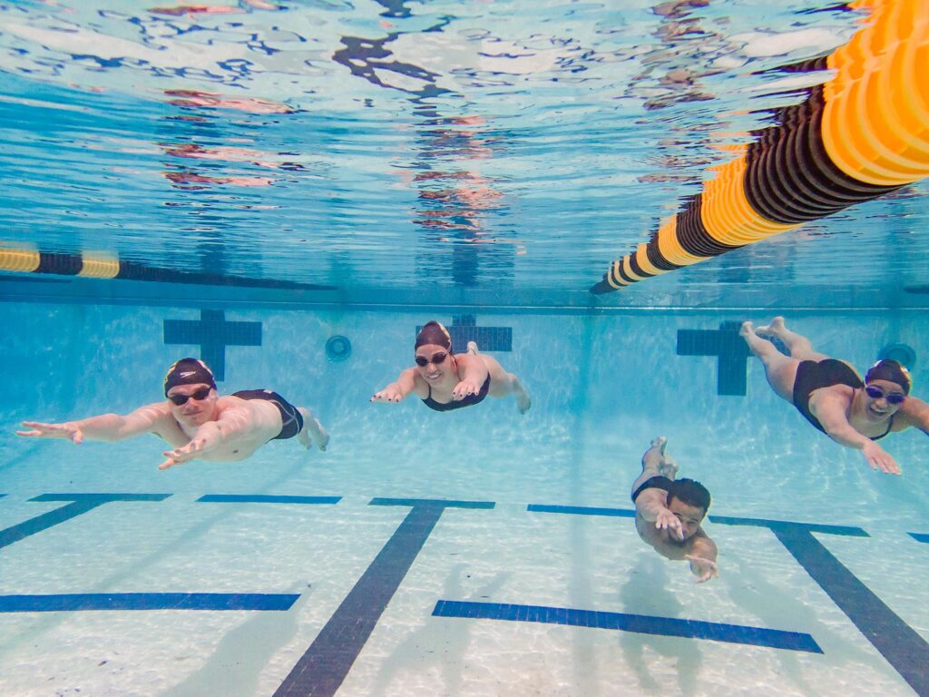 Four friends swimming together in UMBC's pool.