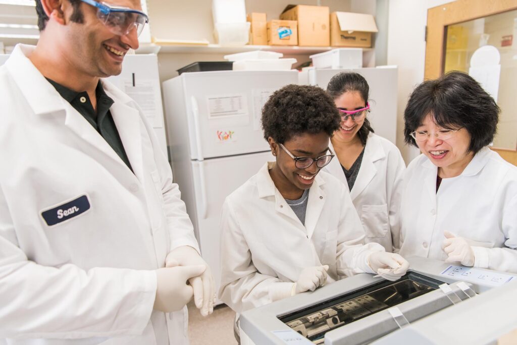 Weihong Lin, biological sciences, (right) works with students in the lab. Photo by Marlayna Demond '11 for UMBC.