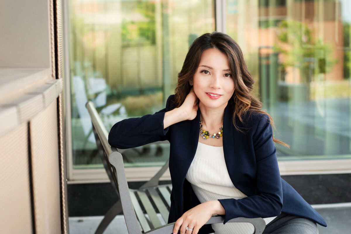 Professional portrait of Charissa sitting outside, wearing a blazer.