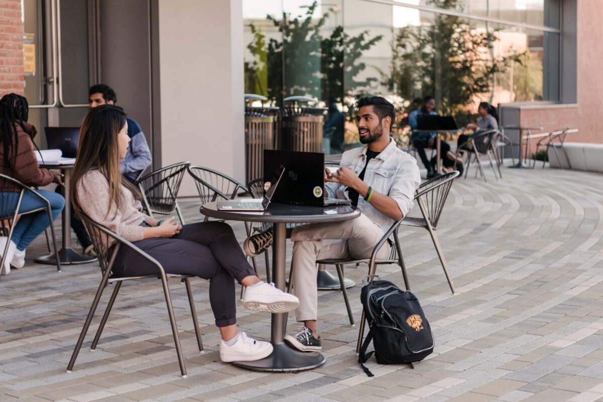 Two students meet together at a table outside