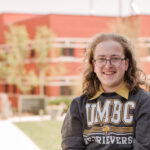 Boy smiling for headshot outdoors in UMBC sweatshirt