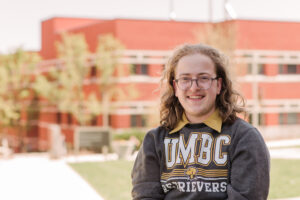Boy smiling for headshot outdoors in UMBC sweatshirt