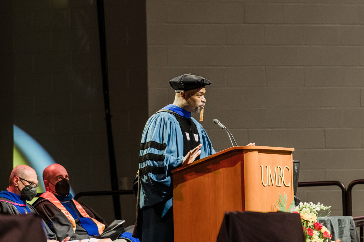 Man speaking at podium in commencement regalia