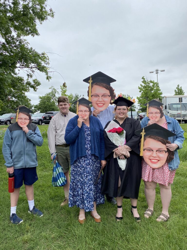 Graduate poses with family members with cut outs of her likeness.
