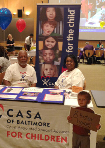 Man and woman sit at an info table with signage "CASA of Baltimore"