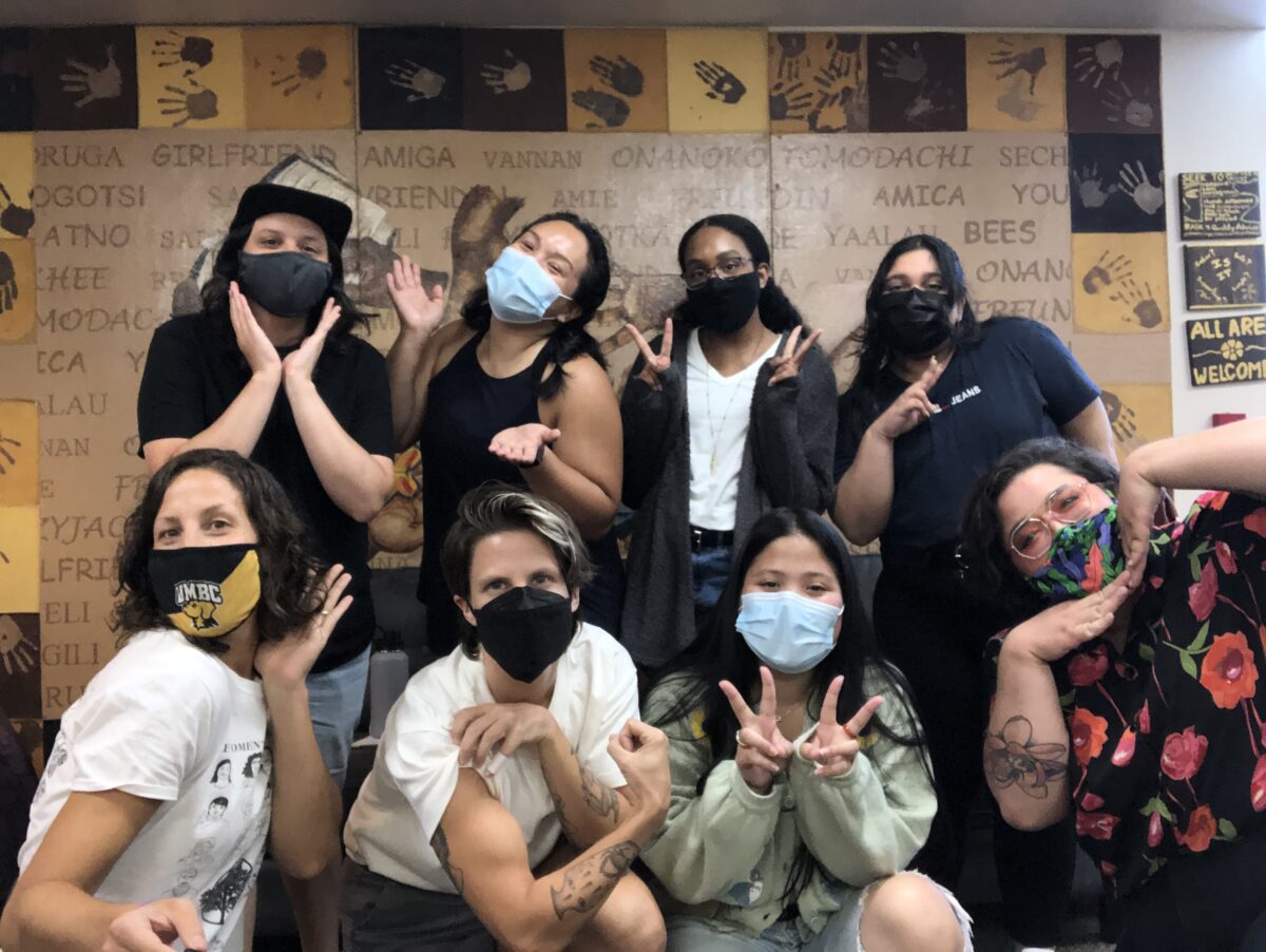 A group of students and staff with masks on striking various poses