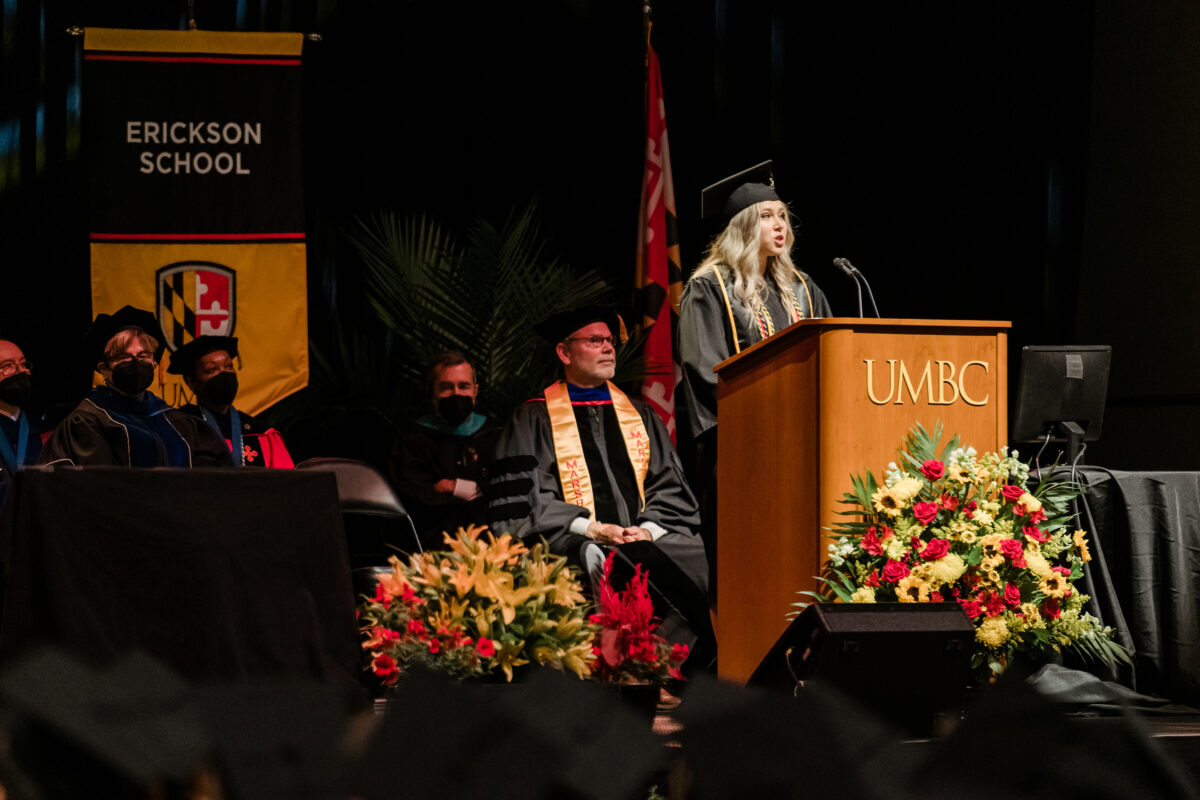 Girl speaking at podium wearing graduation regalia