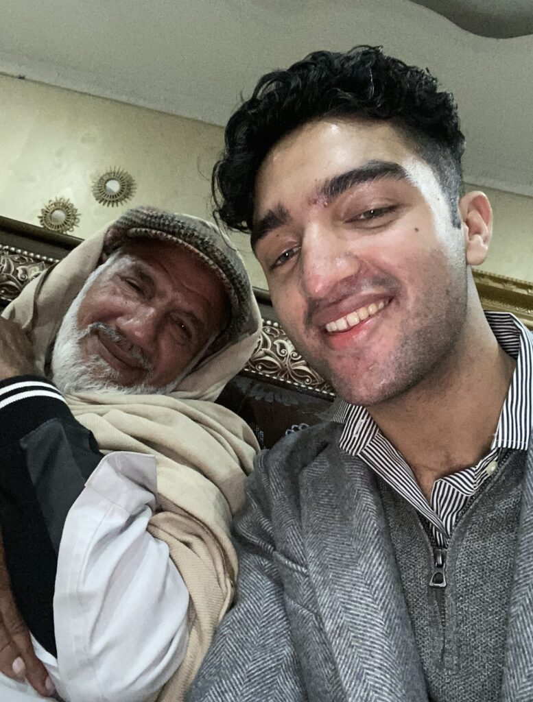 Headshot of two people sitting closely together. One is wearing a turban and the other a striped collar shirt.