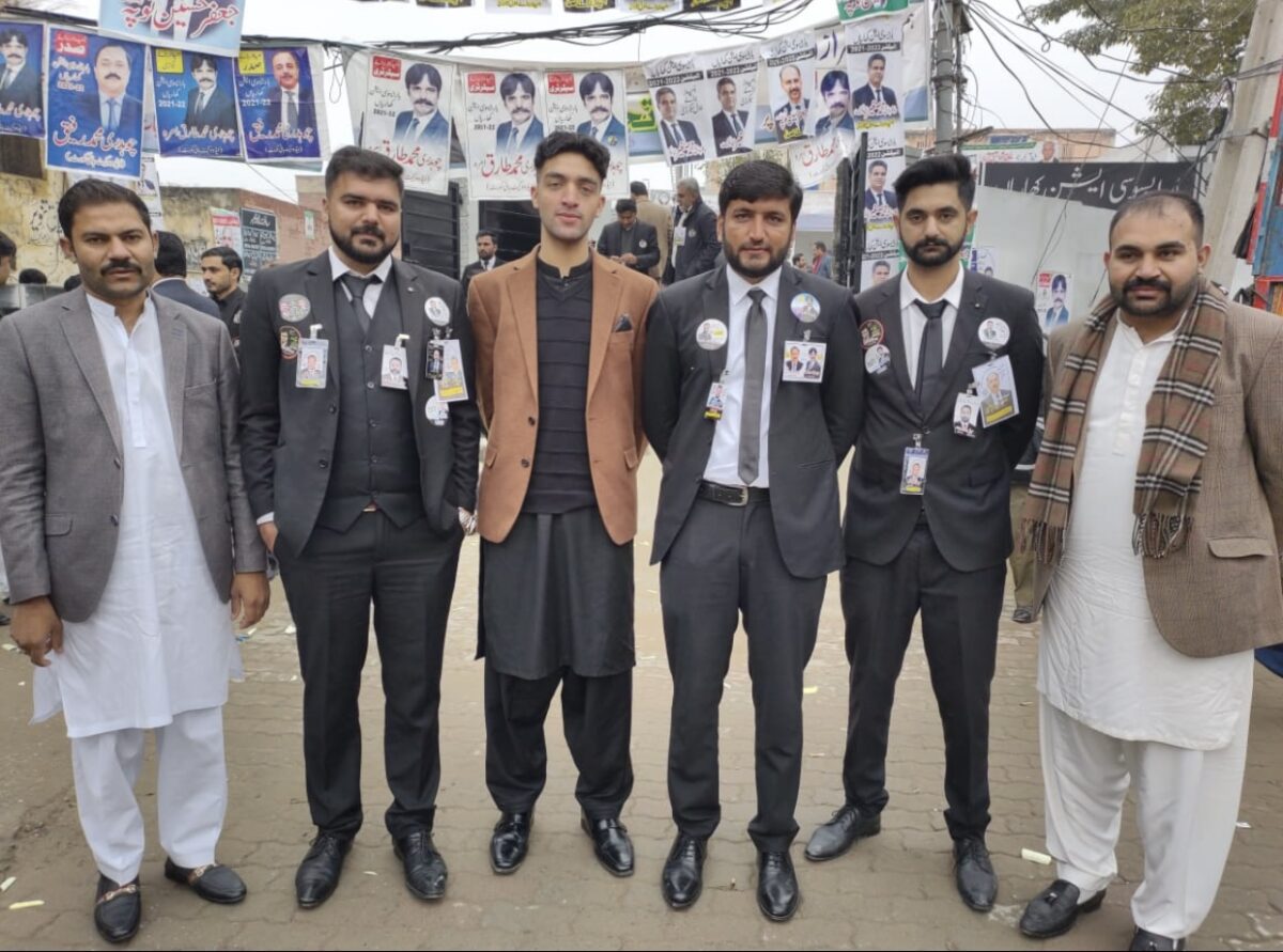 Six adults stand next to each other in a market.