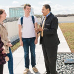 Freeman Hrabowski stands on the roof of the Administration building with three students.