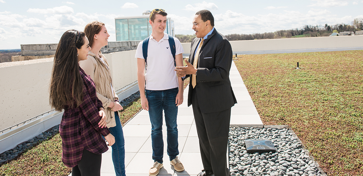 Freeman Hrabowski stands on the roof of the Administration building with three students.