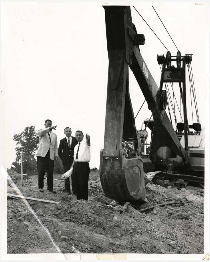 three men point from a construction site