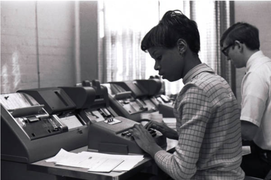 two students work on a 1970s computer system