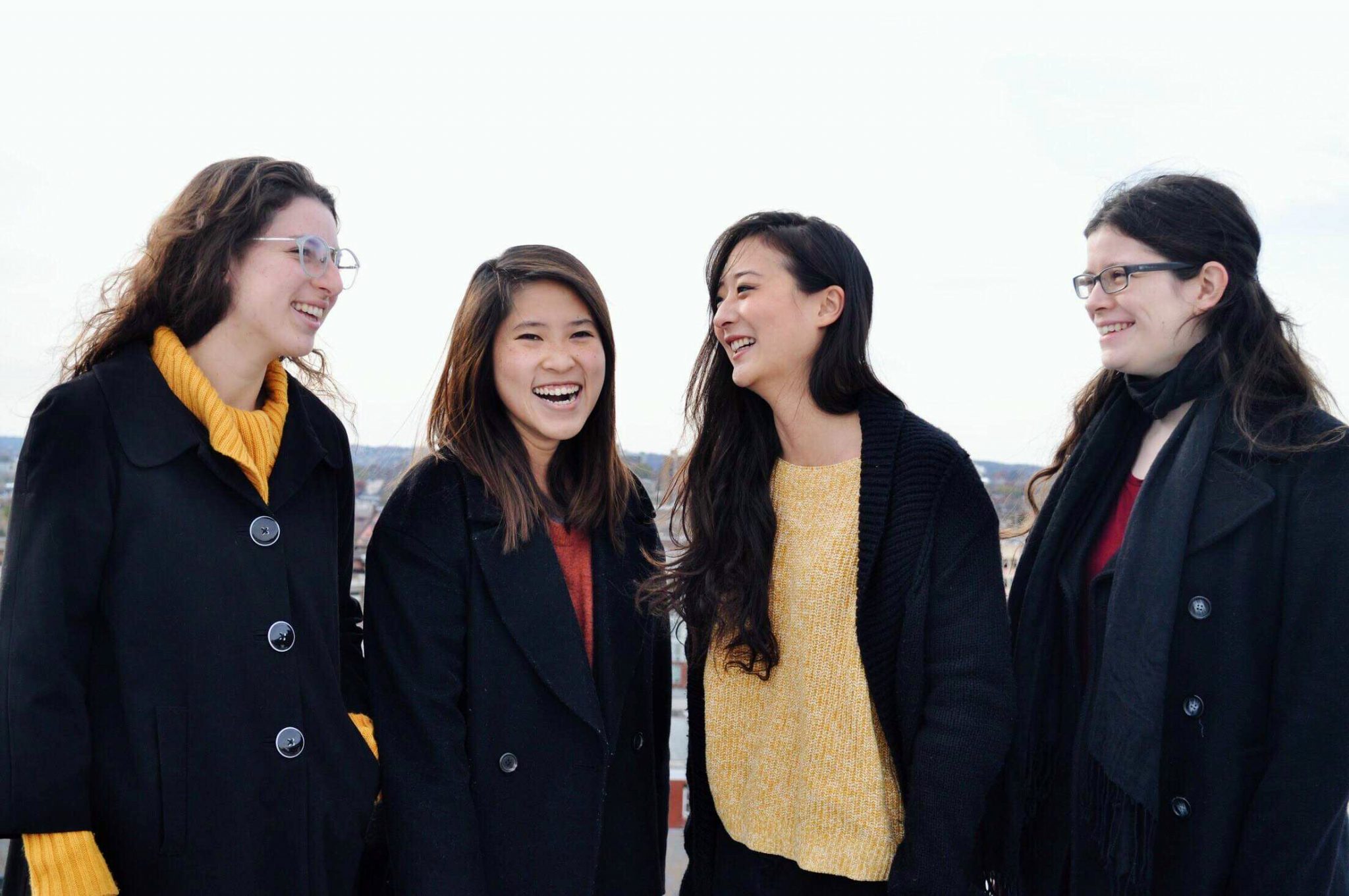 Four women smile and talk against an outdoor background