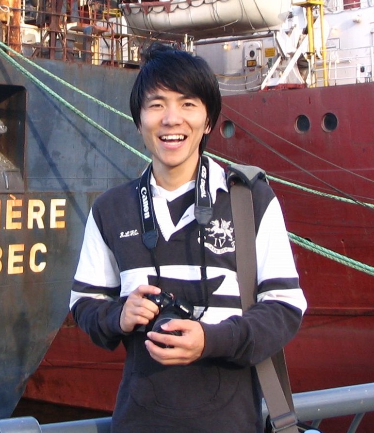 Man in front of cargo ship holds camera
