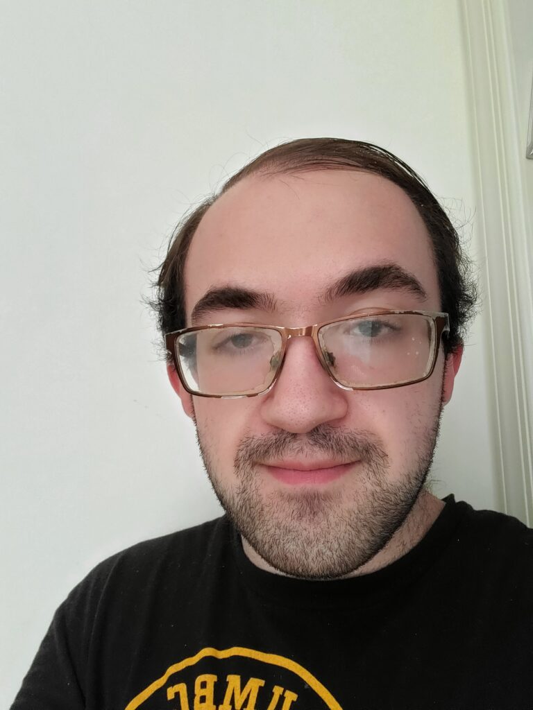 Headshot of Alexander Bauserman, a brown haired man wearing glasses