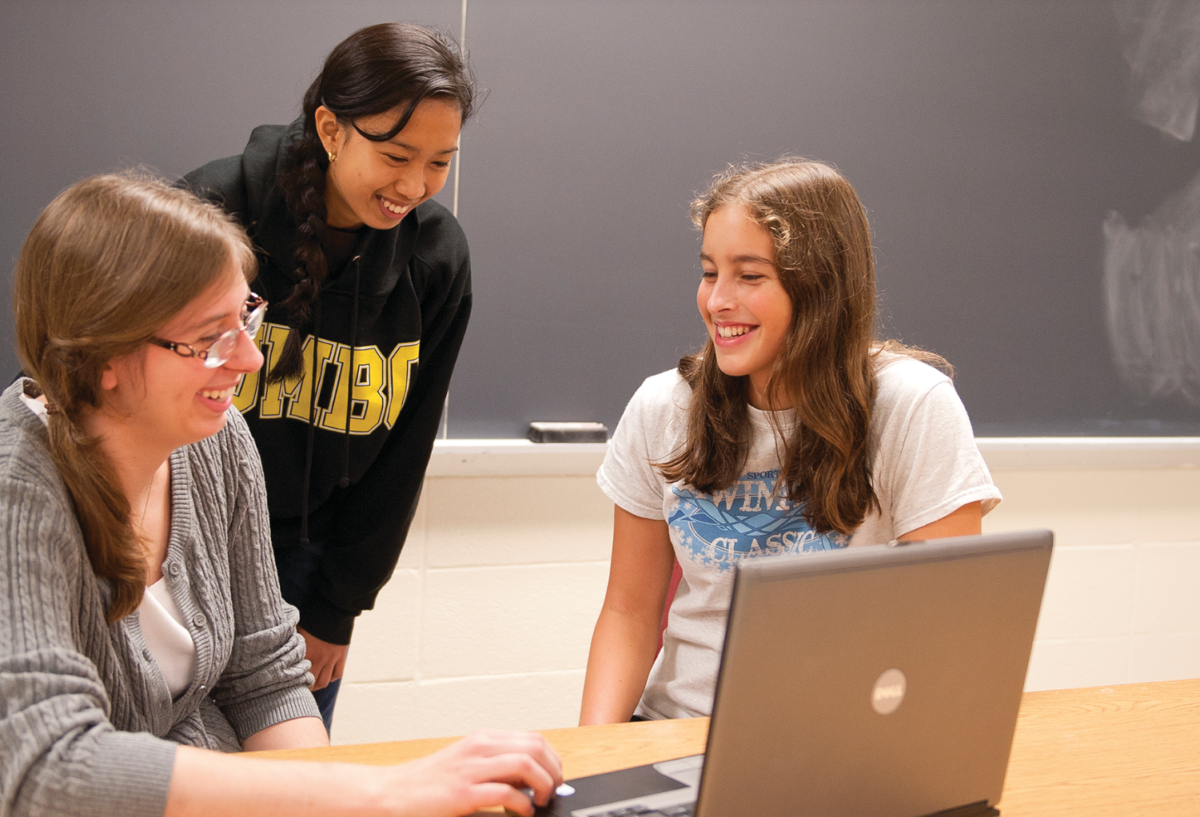 three female students studying something on a computer screen
