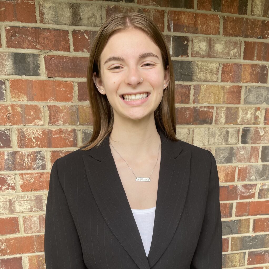 Headshot of Madelyn Pollack in a white shirt and black jacket.