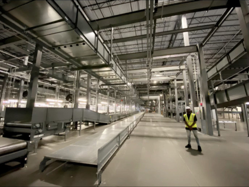 a man stands in a large warehouse with conveyor belts