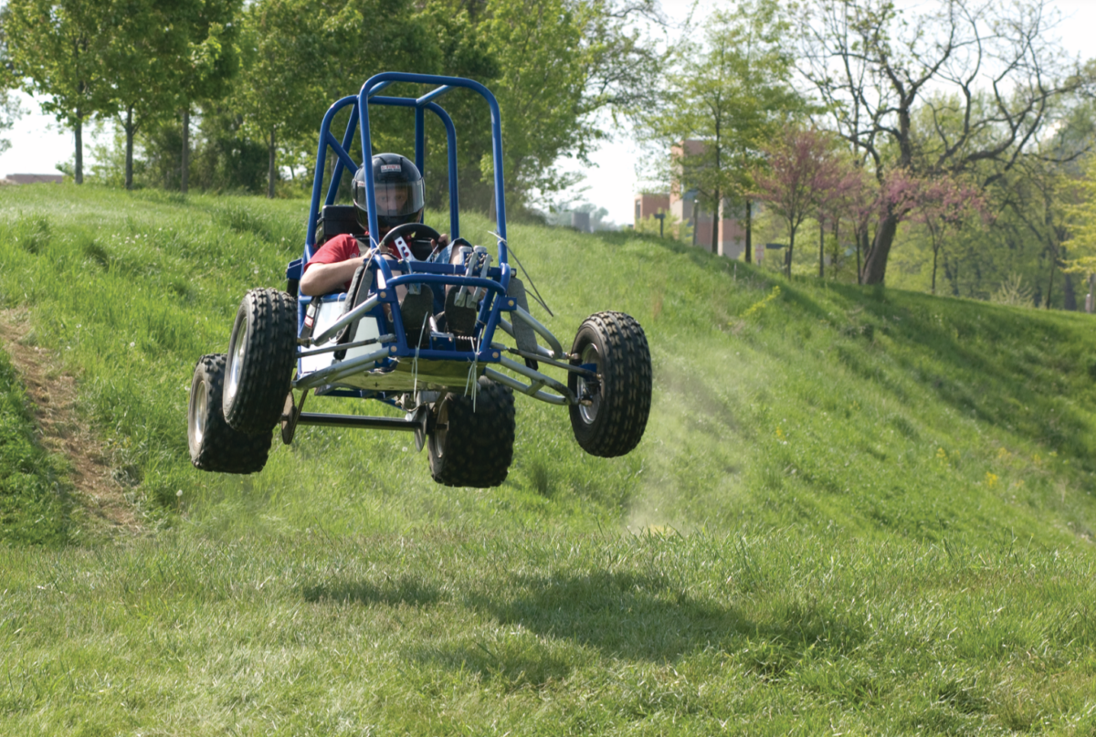 a small homemade vehicle flies over a hill