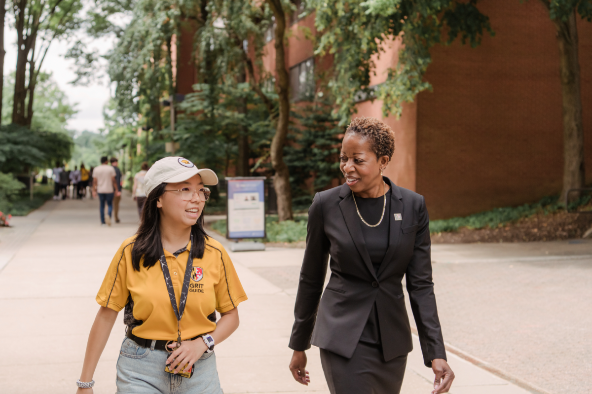 a student and a university president walking down a campus pathway