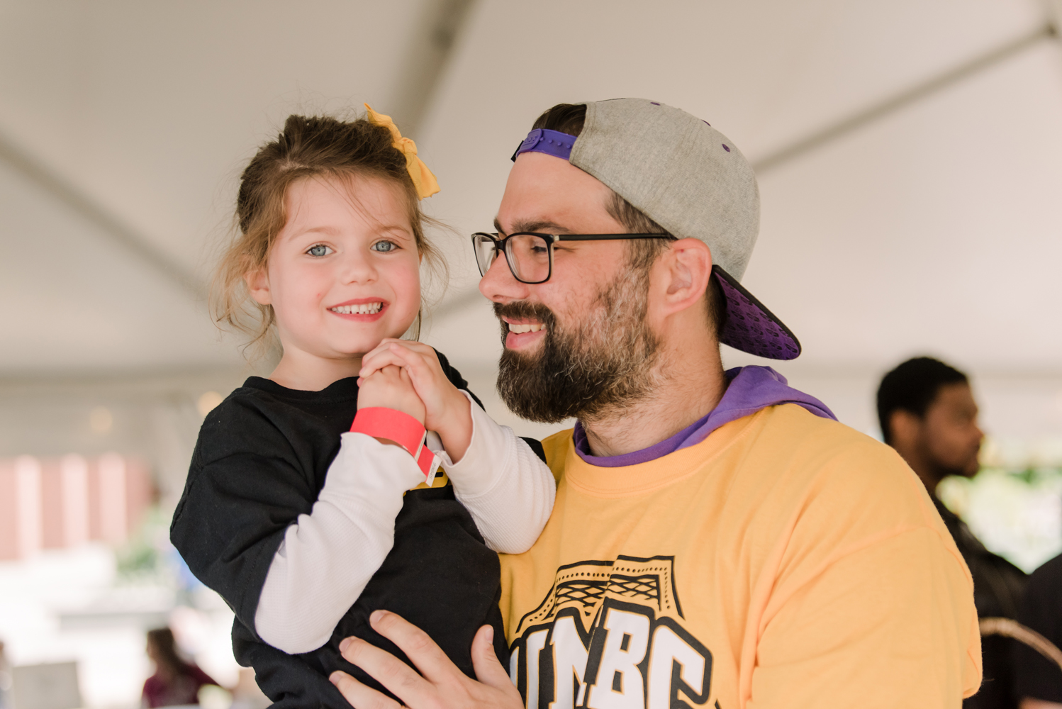 A man holds his daughter in UMBC gear