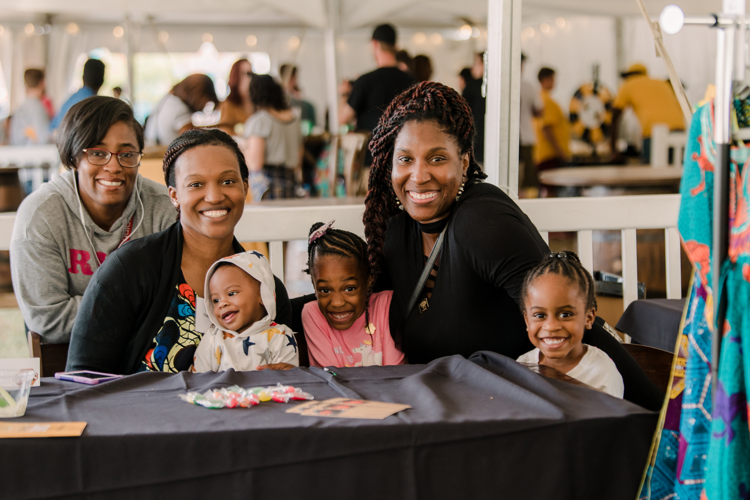 Two women sit with kids at a Homecoming table