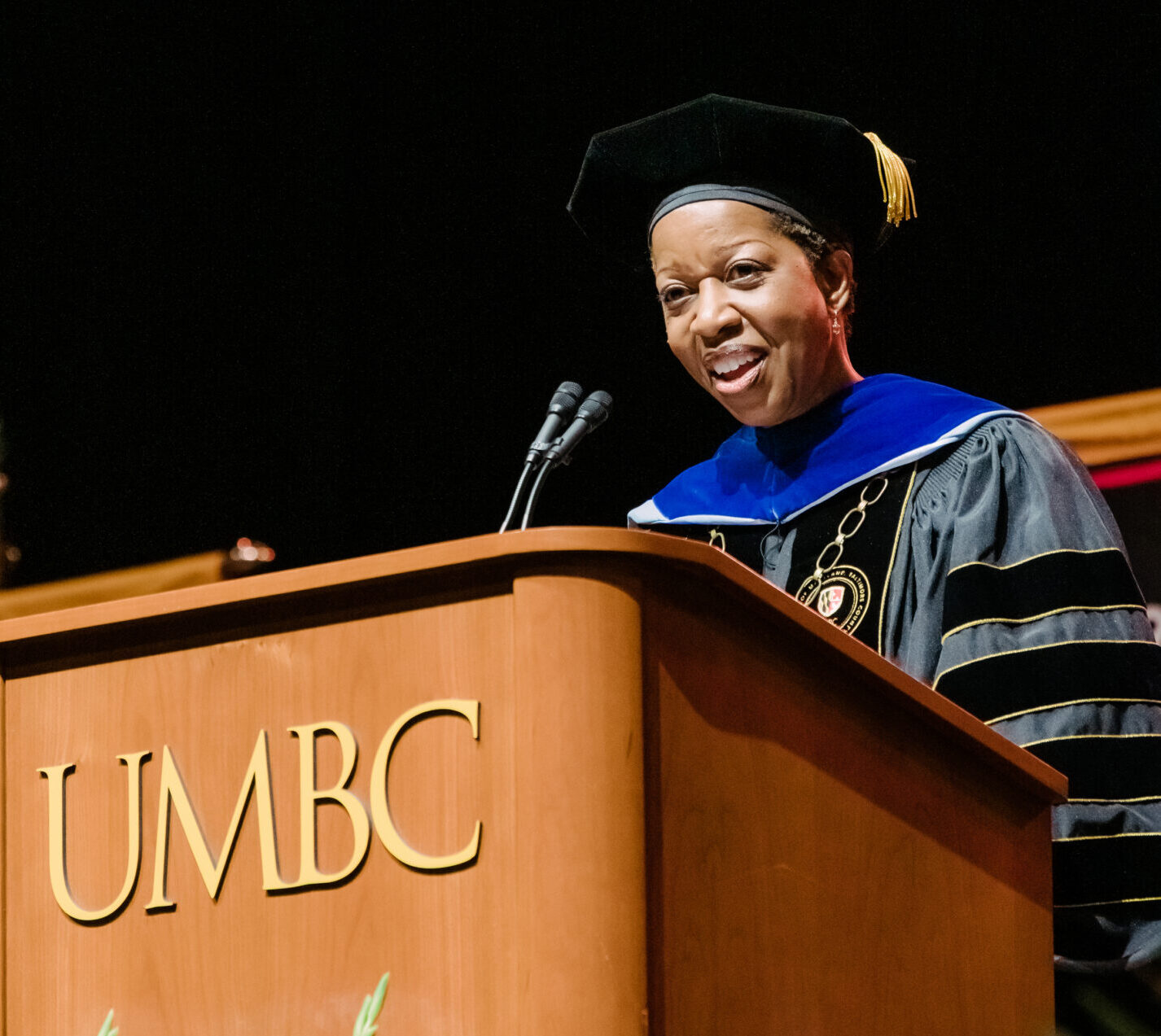 Woman in university regalia speaking at UMBC podium