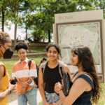 UMBC's president and four students stand in front of UMBC map