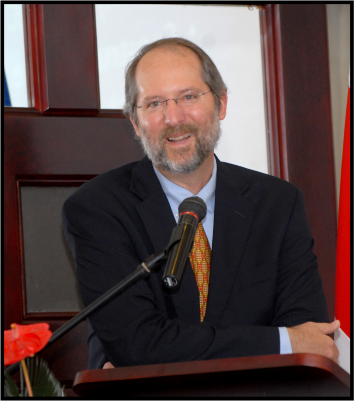 A white man with a beard, wearing a suit, smiles at the camera