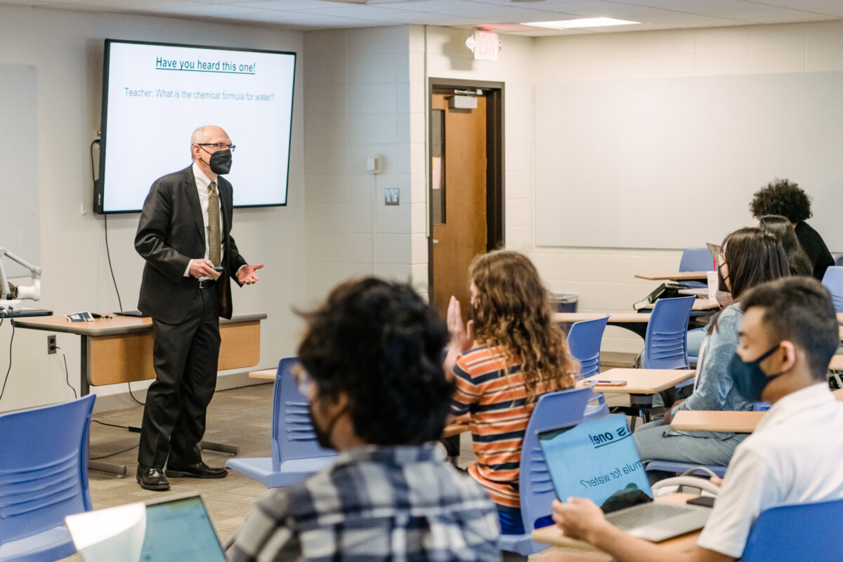 standing faculty member addresses seated students in a classroom