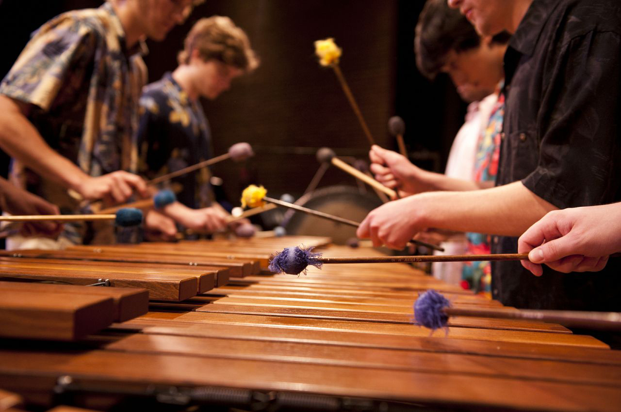 Performers strike a marimba (a percussion instrument) with mallets