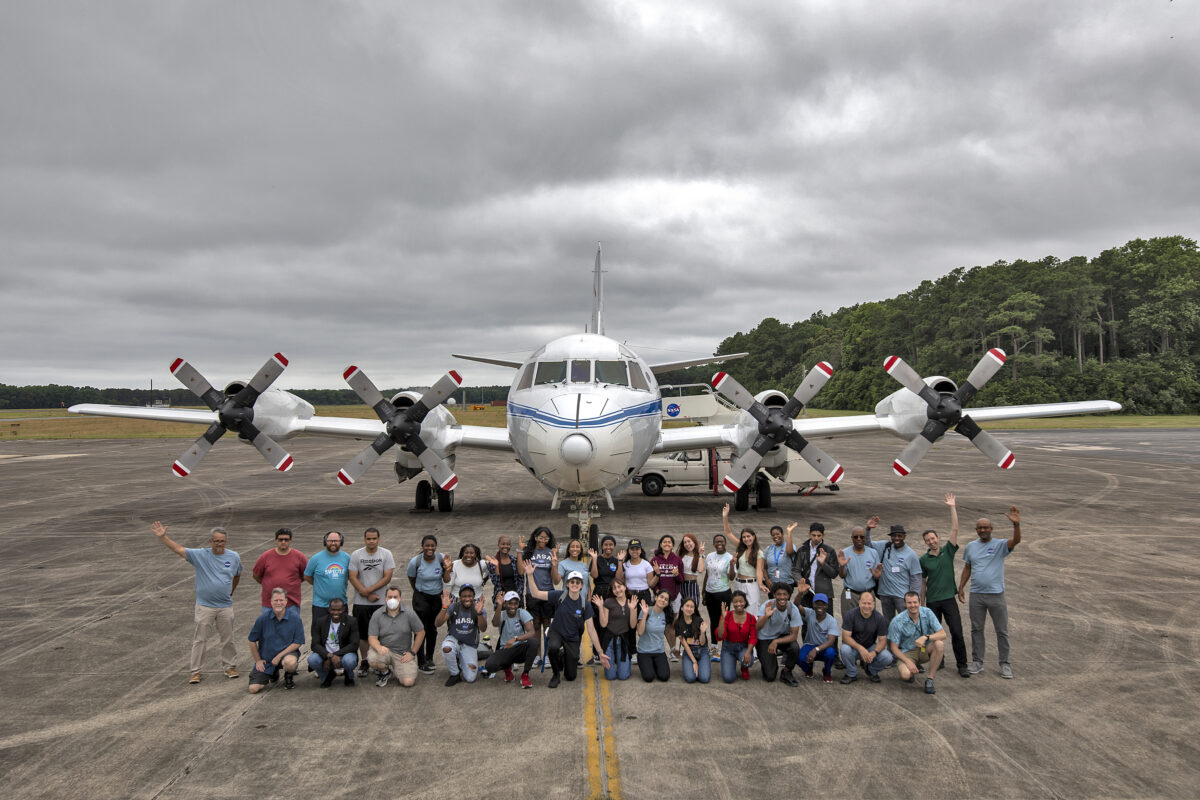 large group on a runway in front of a NASA aircarft; overcast skies
