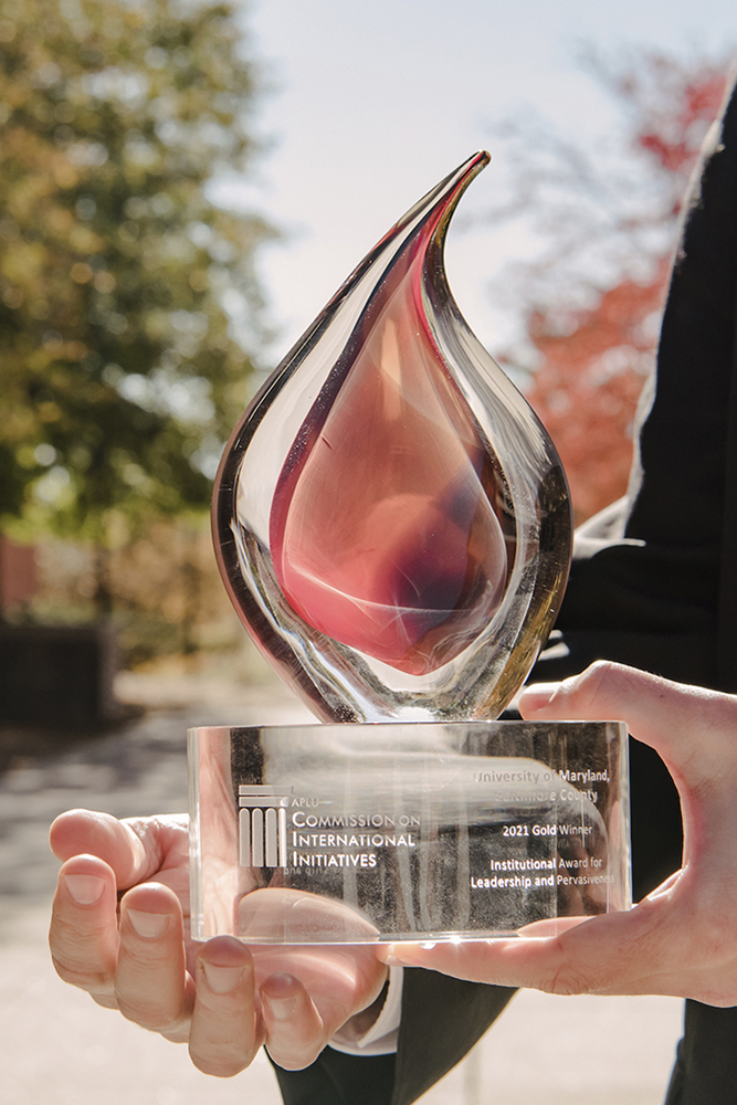 Close-up shot of the APLU award trophy, which is shaped like a flame and made of red and clear glass.