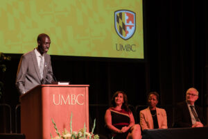 a tall man speaks behind a UMBC lectern
