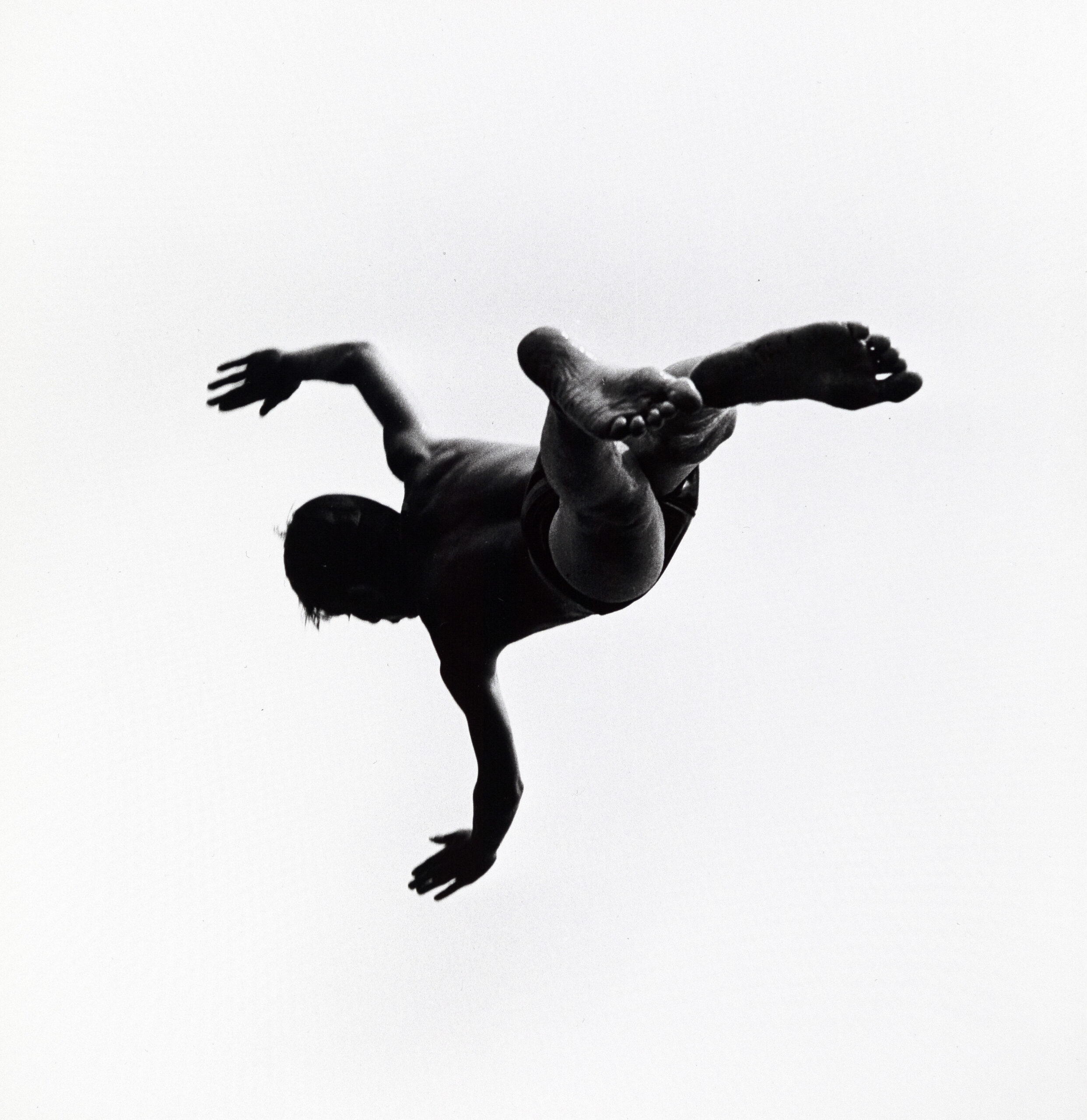 In a black and white image, a man seems to be falling from the sky, surrounded by whiteness
