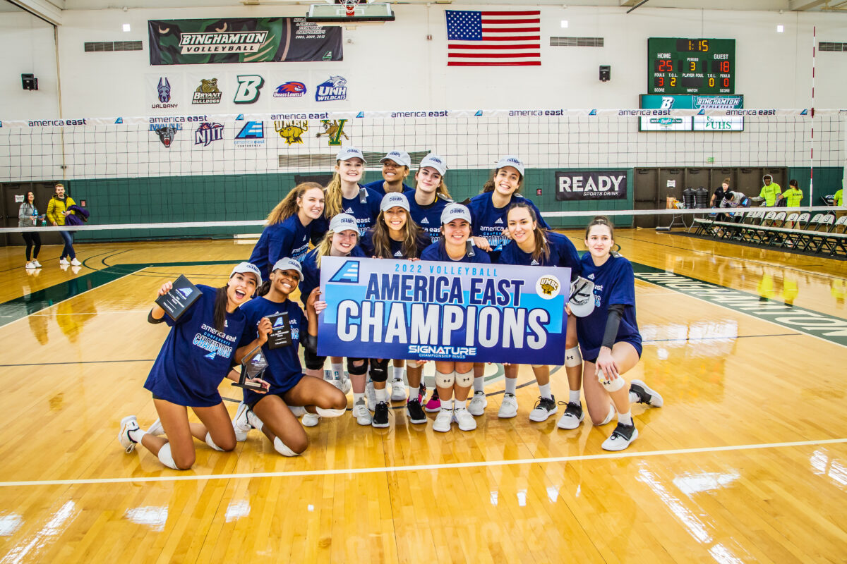 umbc volleyball players holding america east champions sign wearing america east hats