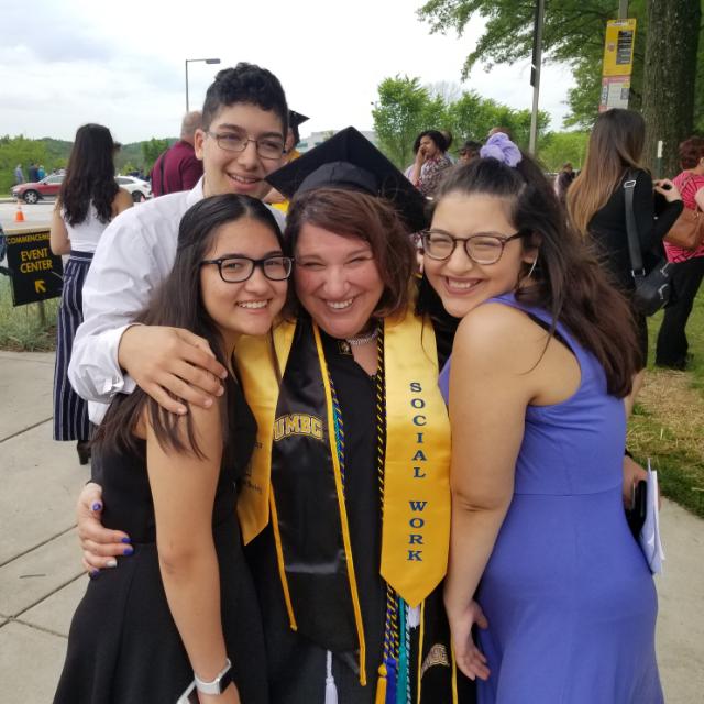 a woman with a social work banner at graduation with family