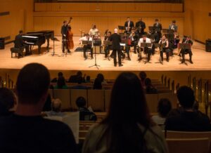 As viewed from the audience, a group of musicians perform on stage