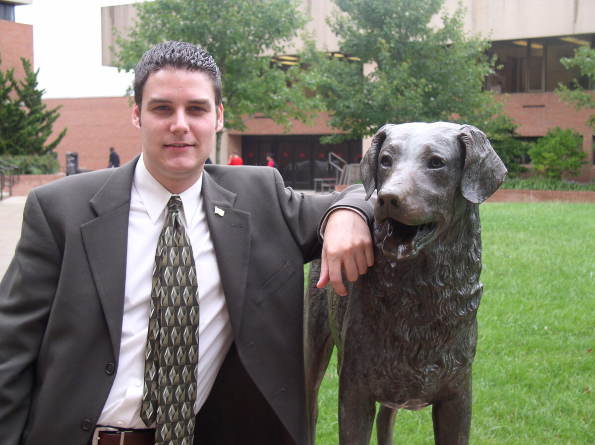 A man stands next to a Retriever dog statue